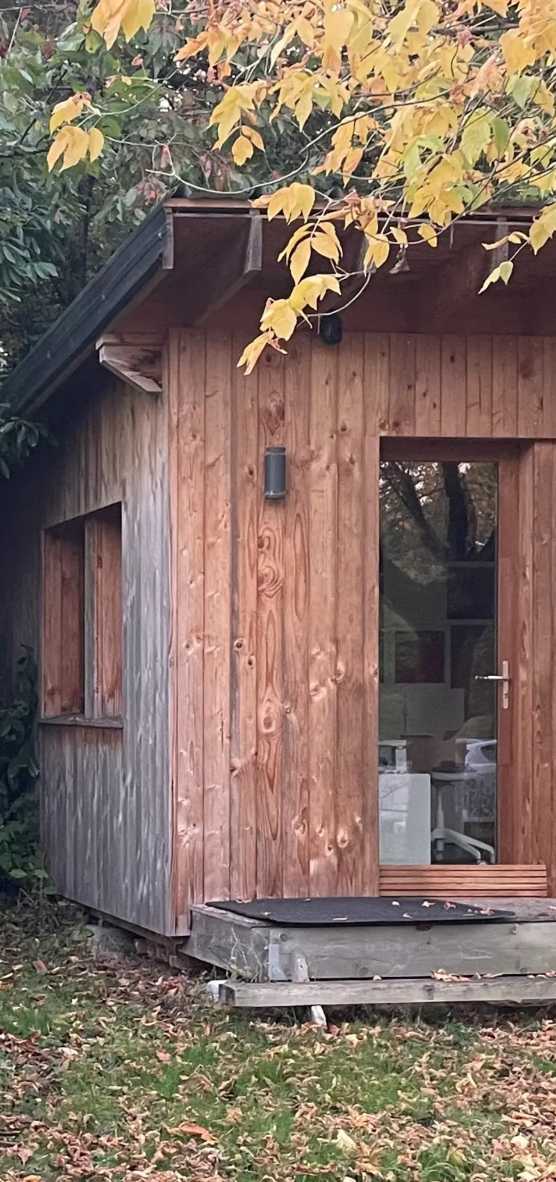 une cabane en bois de réemploi devant un arbre