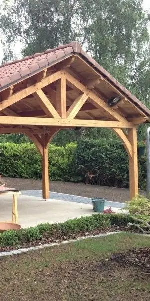 un carport en bois de réemploi sur une propriété avec de l'herbe alentours