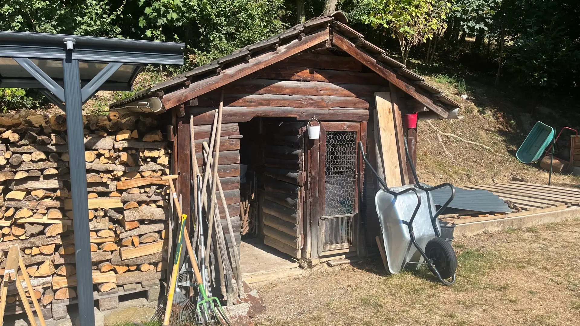 une cabane de jardin avec une brouette posée devant